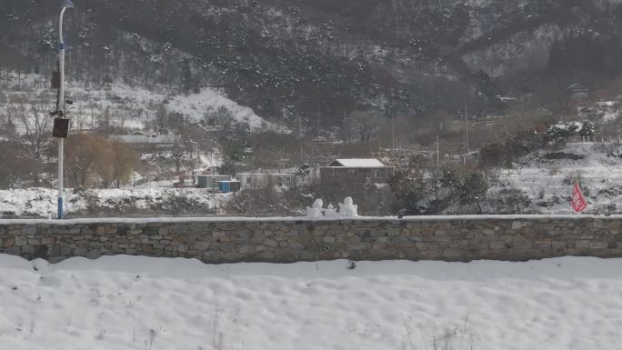 航拍威海里口山水库大坝堤岸上的三个小雪人