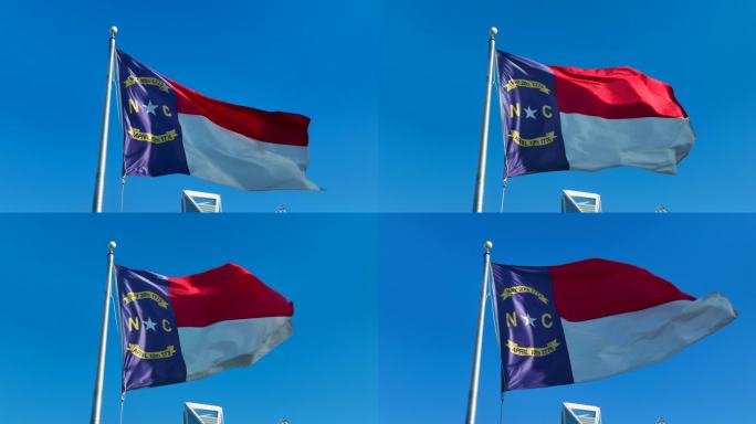 北卡罗来纳州的国旗在明亮的蓝天上飘扬。北卡罗来纳州市中心的静态航拍照片。