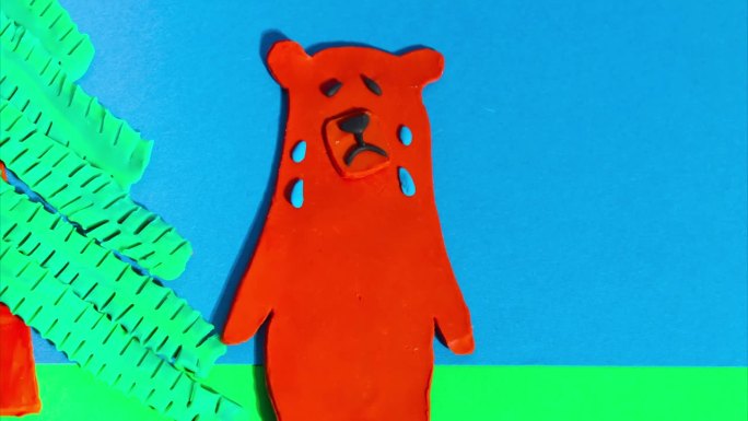 定格动画从橡皮泥。一只大棕熊在蓝色背景上哭泣