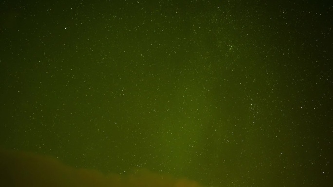美丽的北极光闪耀在繁星点点的夜空中，流星体落下。云慢慢移向画面