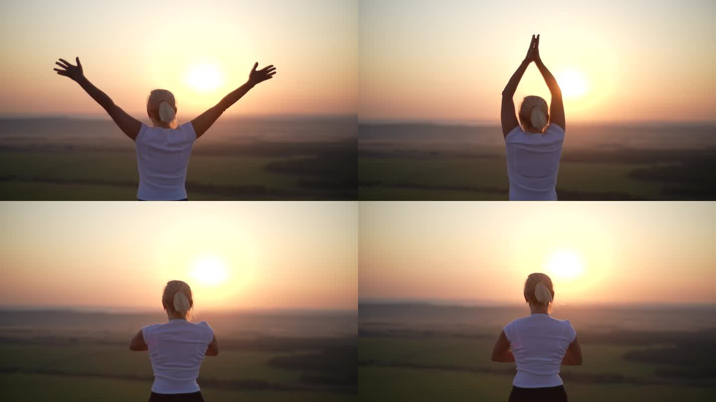 无法辨认的瑜伽女修行者的后视图，独自站在美丽的夏日风景的山顶上练习瑜伽，合十感恩手印