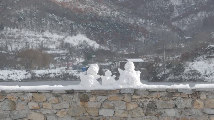 航拍威海里口山水库大坝堤岸上的三个小雪人