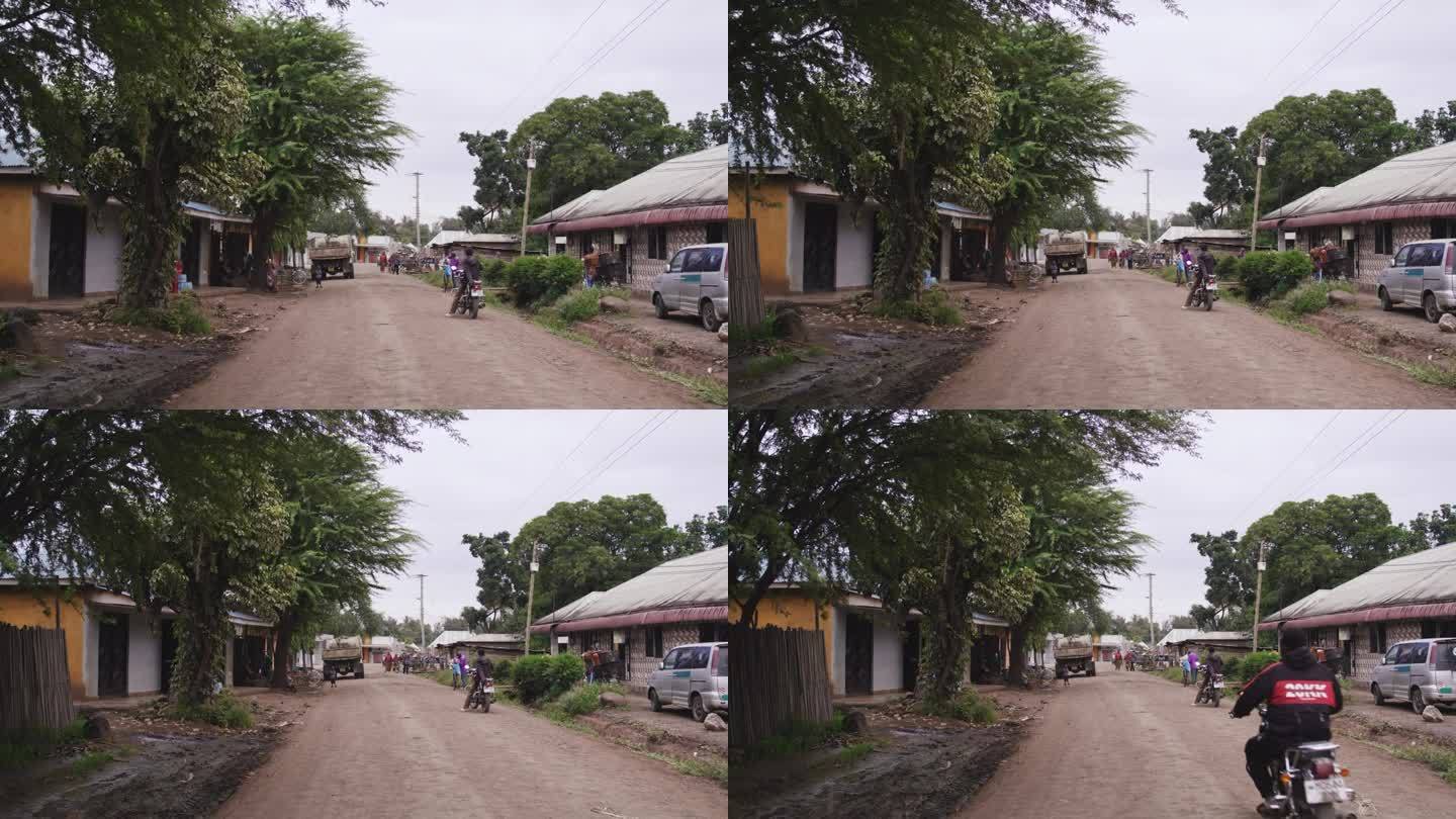 村中土路的视野逐渐缩小。农村地区车辆和人的慢镜头。房子的外部。