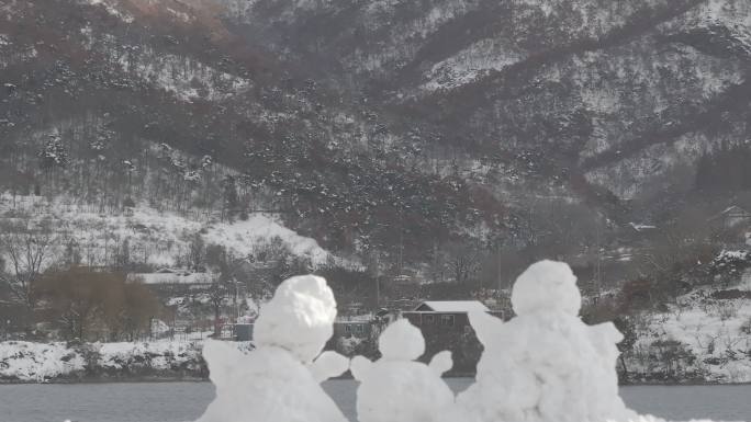 航拍威海里口山水库大坝堤岸上的三个小雪人