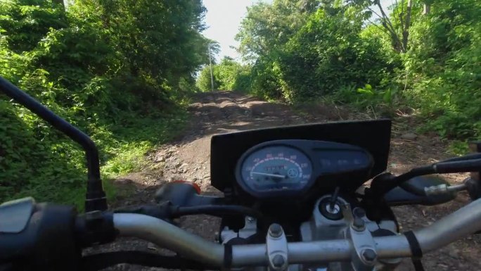 摩托POV:摩托车爬上陡峭的车辙，侵蚀的乡村土路