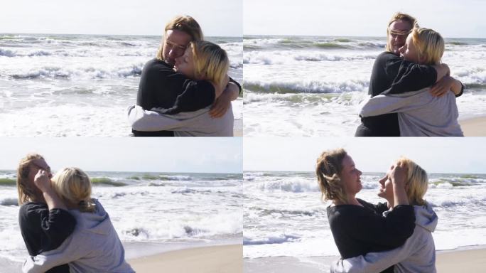 美丽的母亲在大海的背景下拥抱着她心爱的女儿。