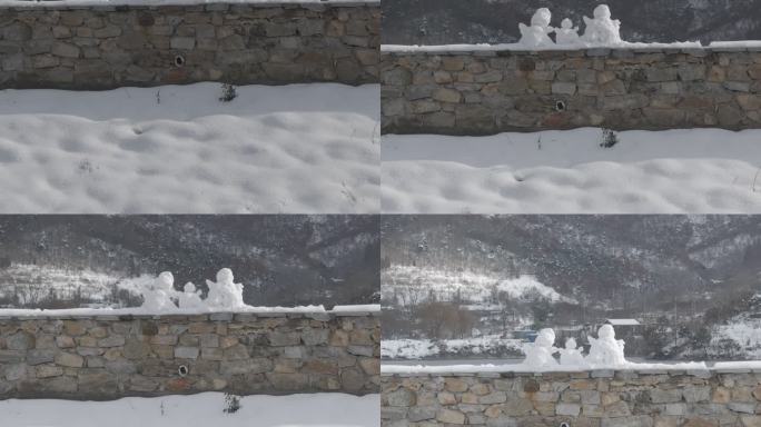 航拍威海里口山水库大坝堤岸上的三个小雪人