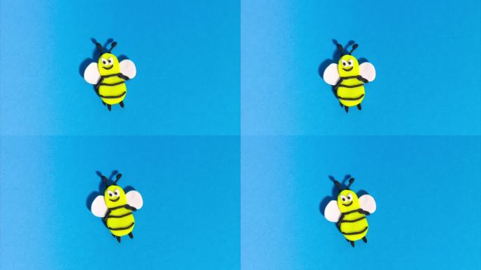 定格动画从橡皮泥。欢快有趣的蜜蜂在蓝色背景上飞翔