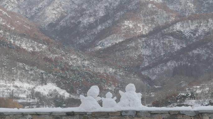 航拍威海里口山水库大坝堤岸上的三个小雪人