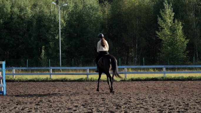 在马术俱乐部骑马。骑手赛前训练。一个骑马的年轻女子，在马术俱乐部里骑马。在训练场上骑马的女骑手。