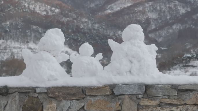 航拍威海里口山水库大坝堤岸上的三个小雪人
