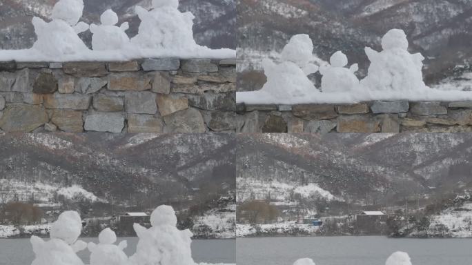 航拍威海里口山水库大坝堤岸上的三个小雪人