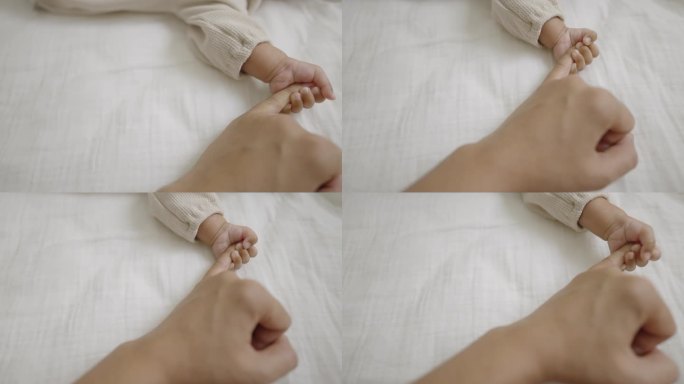 慢镜头:一个小男孩在床上睡觉时紧紧抓着妈妈的手指。