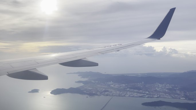 客机机上角度拍摄逆光高空中飞行的机翼海岛