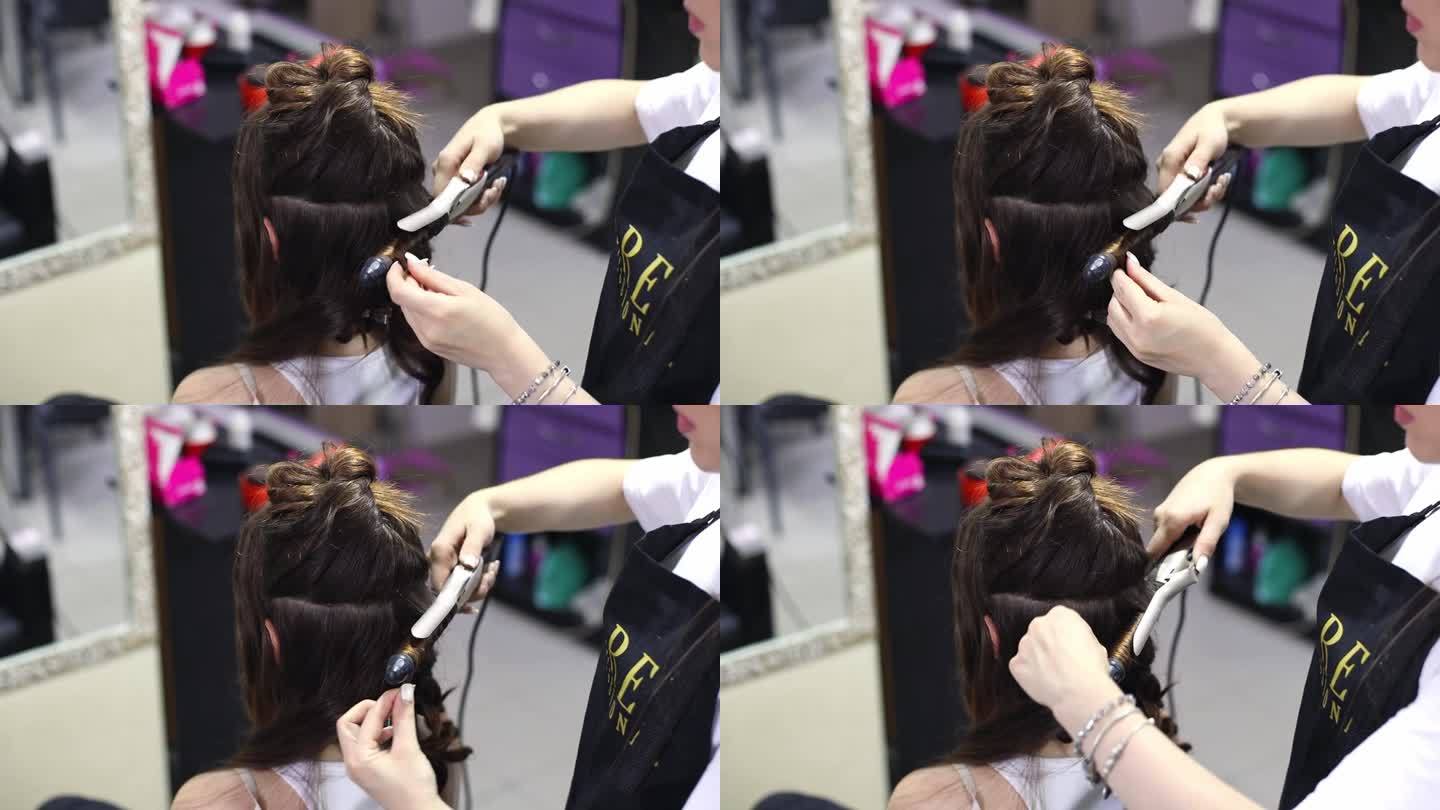 理发师用卷发棒把一个女孩的一缕头发卷起来，给她做头发。