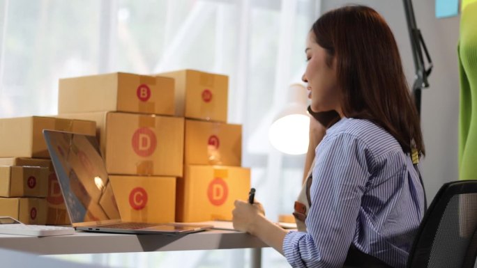 亚洲女商人，一家网上购物公司的老板，在家工作，打电话给客户，检查包裹箱是否有货物送达。