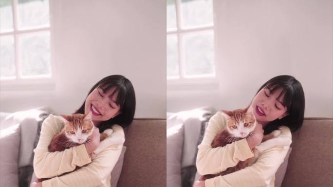 一名亚洲女子深情地抚摸着她的橙色猫咪，在家里散发着快乐和关怀。捕捉宠物情感的幸福时刻，创造温暖人心的