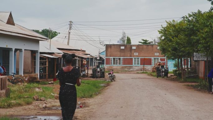 SLO - MO拍摄的女人走在路上，走向村里的房子。她穿着传统服装。
