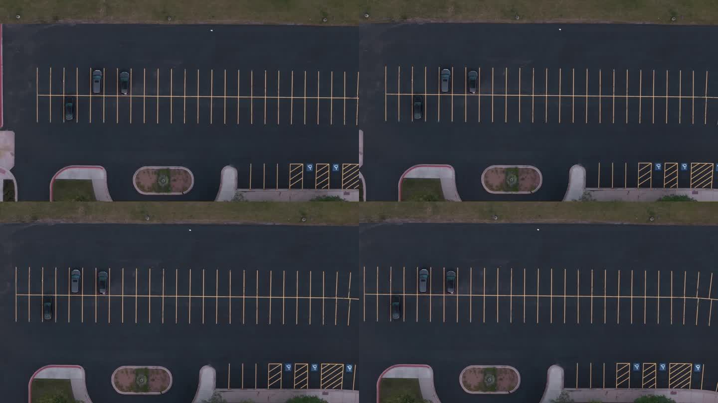 从上到下的无人机拍摄的晚上一个空荡荡的黑色停车场的画面。移动拍摄