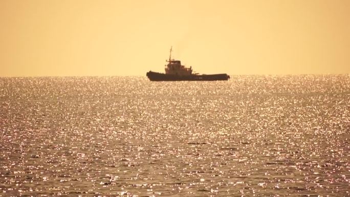 在平静的大海上，拖船在日落时返回港口，帮助大型集装箱船操纵。鸟瞰图、海运业、海洋运输或商业概念。