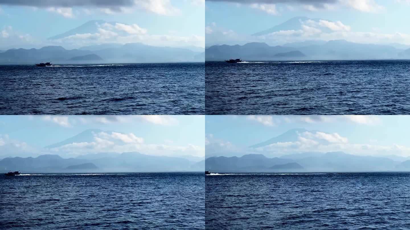 一艘船在水里移动，前面有一座大山