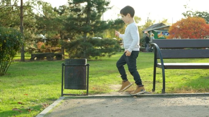 一个男孩在公园的垃圾桶里扔垃圾
