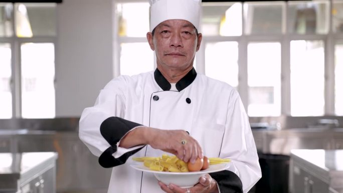 亚洲中年厨师拿着优质食材走向镜头，由专业厨师长呈现的优质卫生餐厅，肖像厨师讲师拿着鸡蛋和意大利面