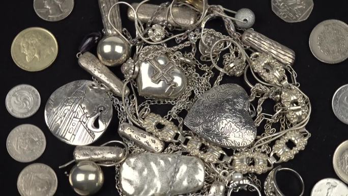古老的各种银饰和硬币躺在黑色的背景上