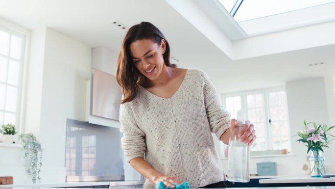在家厨房做家务的妇女用抗菌喷雾清洁剂擦拭和清洁表面