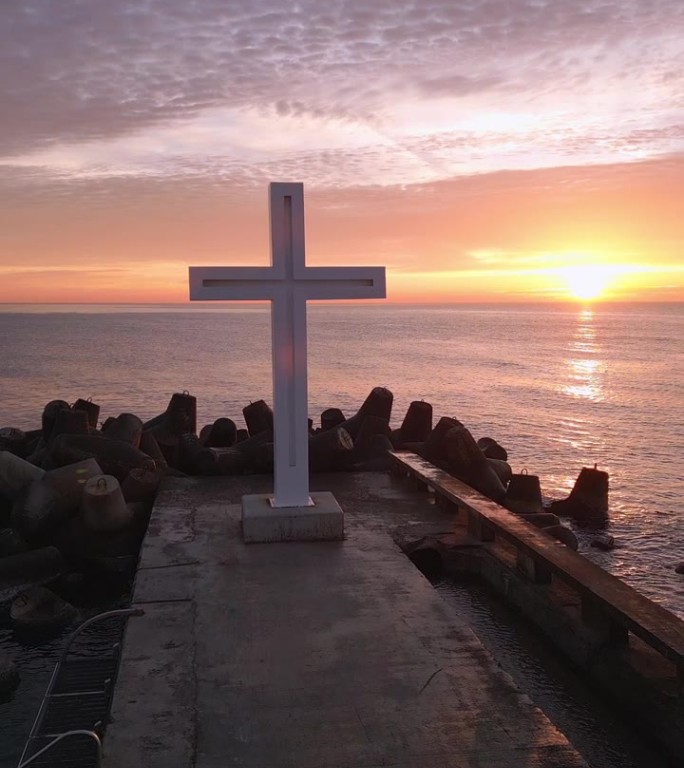 绕行，绕行清晨日出时环绕基督教圣十字架的飞行大十字架矗立在海岸防波堤的边缘