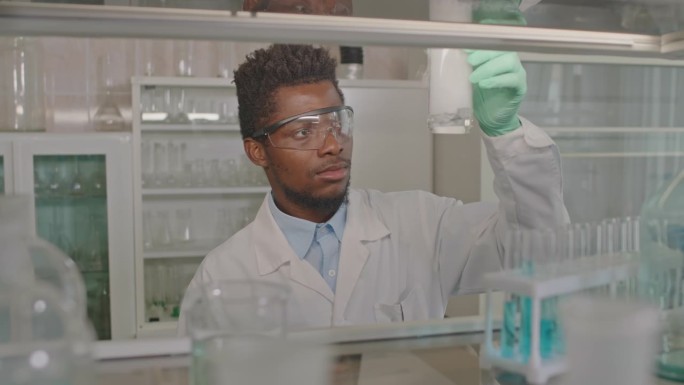 黑人男性科学家观察量杯中的化学反应