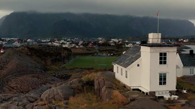 典型斯堪的纳维亚白房子的特写和石崖顶上的灯塔。