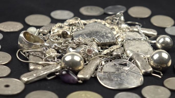 古老的各种银饰和硬币躺在黑色的背景上