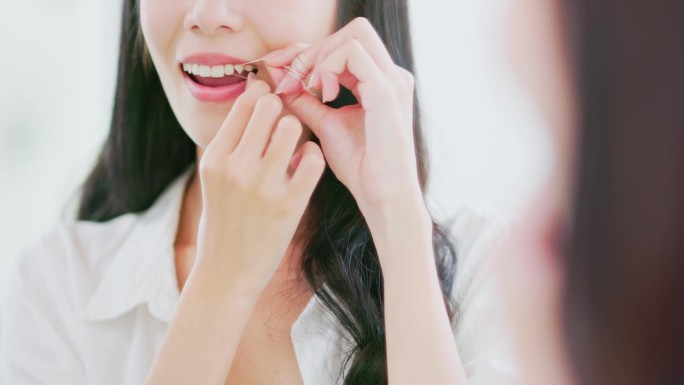 亚洲妇女愉快地用牙线剔牙