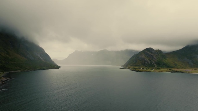 史诗般的全景广阔的水面之间的常绿北欧峡湾山峰，隐藏在雾。无人机的观点。