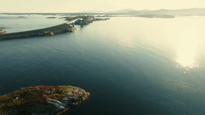 无人机在美丽的海面上飞行，被明亮的阳光覆盖，背景是史诗般的斯堪的纳维亚景观
