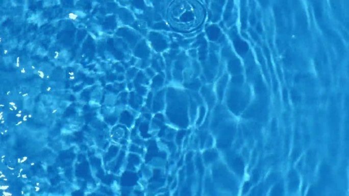 蓝蓝的水面上泛起涟漪。离焦模糊透明黑白彩色清晰平静水面纹理飞溅和泡沫。水波与闪亮的图案纹理背景。