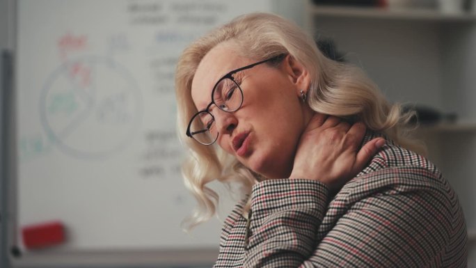 女性在办公室用笔记本电脑工作后感到颈部疼痛，久坐不动的生活方式