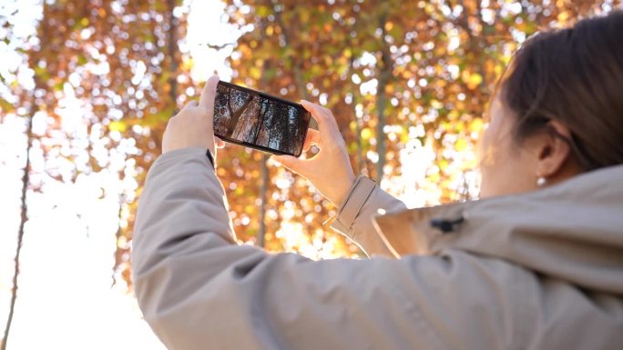女人在秋天用手机拍照