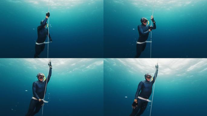 自由潜水员靠绳子练习并上升。自信的男性自由潜水员在开阔的海面上沿着绳索训练，然后从深处上升