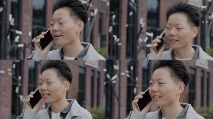 快乐的亚洲人走在城市街道上，用手机聊天，享受谈话的特写
