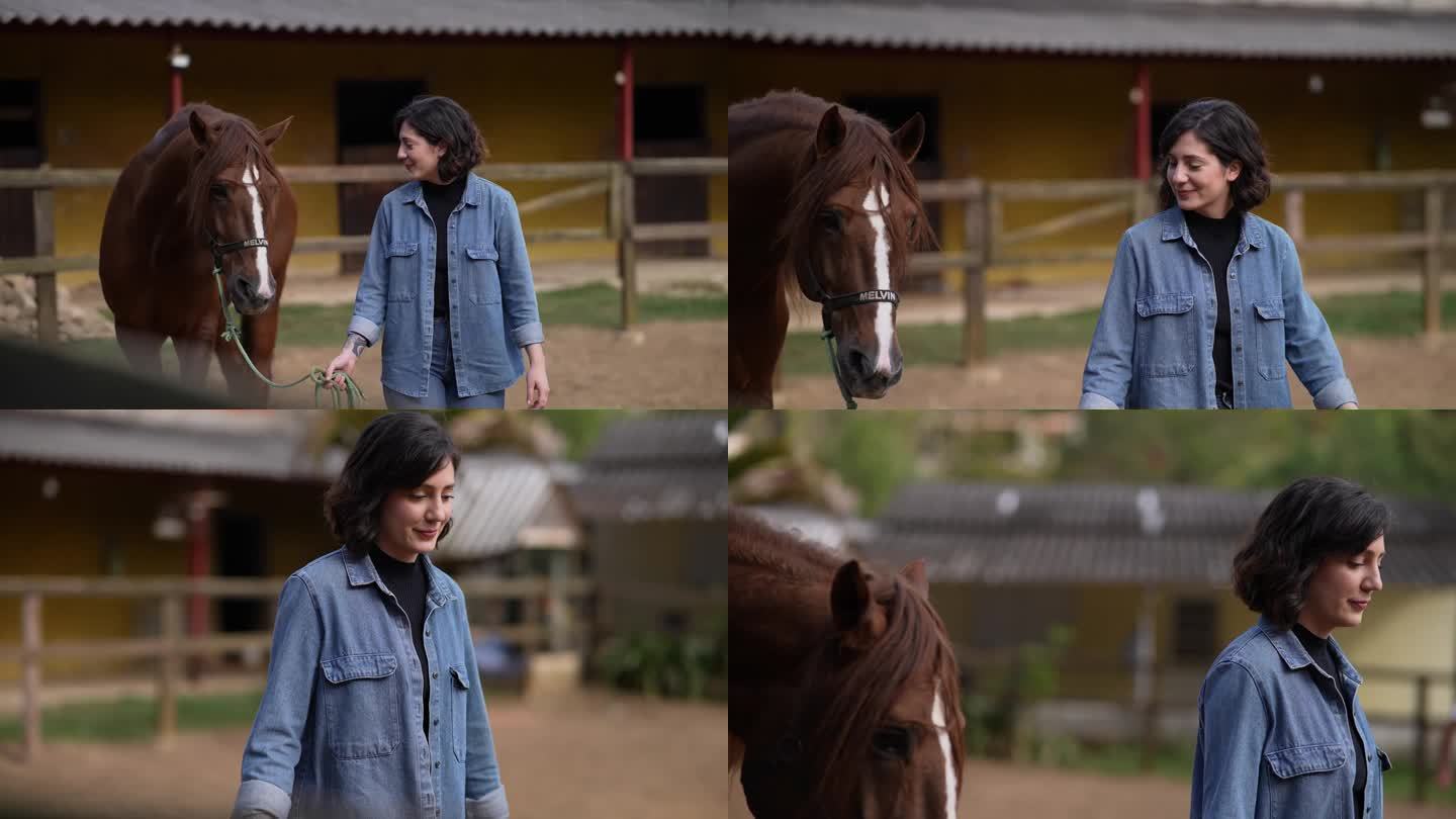 年轻女子牵着她的马在马厩里散步