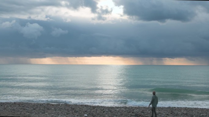 一个成熟的男人走在空旷的海滩上
