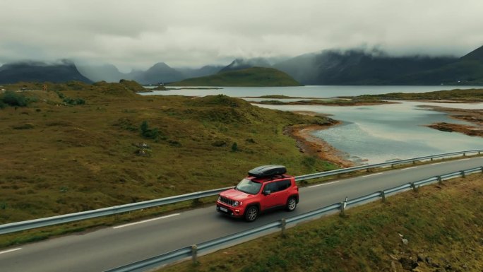 红色SUV在美丽的斯堪的纳维亚风景中行驶的鸟瞰图