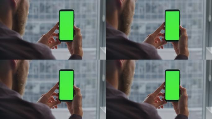大胡子在室内用绿屏手机。检查模型屏幕的人