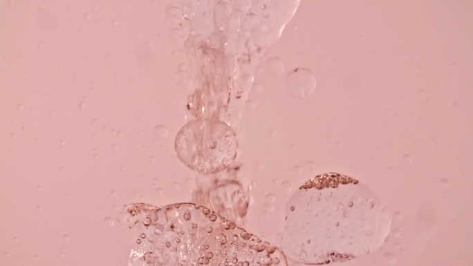 微距拍摄的各种气泡在水中上升在浅白色的背景。液体乳霜凝胶透明化妆品样品纹理与泡沫。清洁和纯净的理念。