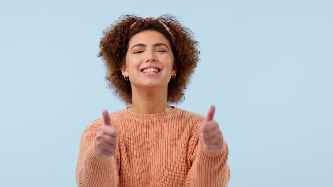 脸，微笑和竖起大拇指的女人在演播室感谢你，动机或成功在蓝色背景。快乐，肖像和女士模特用表情符号表示支