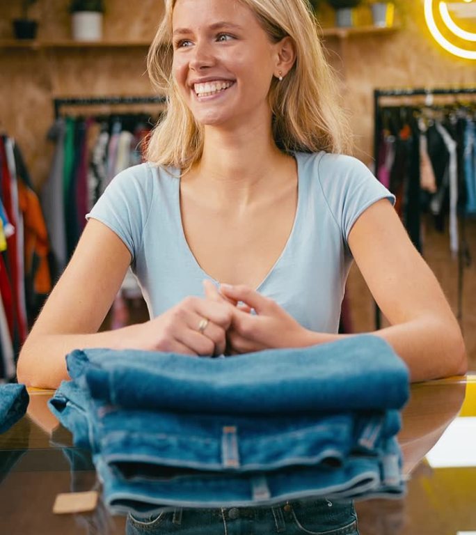 垂直视频肖像的女性销售助理整理库存牛仔裤在时装或服装商店