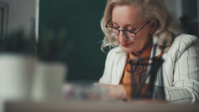 优雅的女老师在教室里检查学生试卷的特写