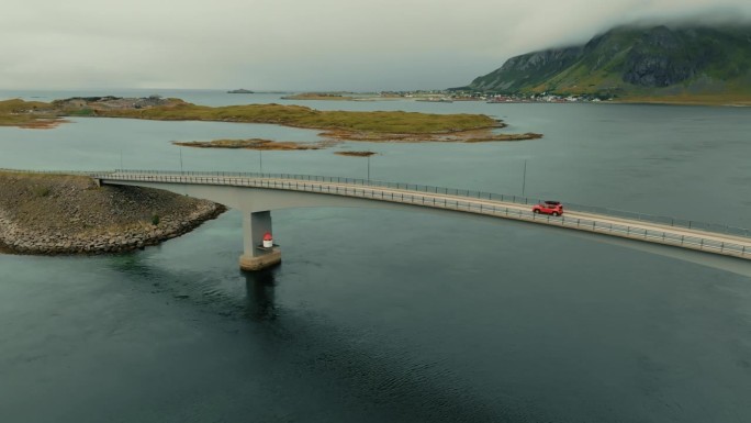 在一个晴朗的日子里，红色SUV驶过一座连接北欧小岛的桥